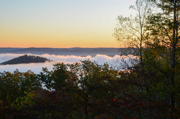Early morning fog blankets the valley below. On a sunrise fall morning.
