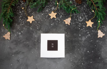 green spruce branches on a dark gray background and a present box with the inscription 