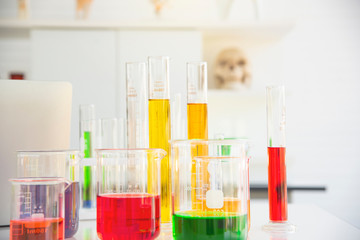 Several test tubes and solution beakers in a science laboratory with liquid of different colors on the laboratory table for chemical background