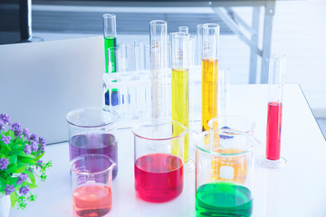 Several test tubes and solution beakers in a science laboratory with liquid of different colors on the laboratory table for chemical background