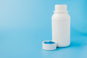 Blue capsules, pills on a blue background. Capsules in a white jar. Vitamins, nutritional supplements for women's health