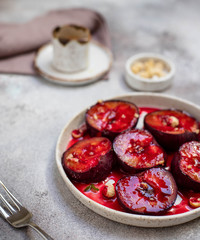 baked ripe plums with honey, cinnamon and nuts. healthy fruit dessert. light background