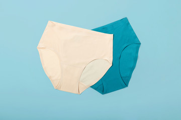 Women blue and beige panties on blue background. Minimal flat lay.