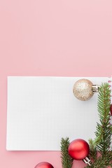 New year concept. Goals list in notepad, gift box and christmas decoration on pink pastel color with copy space