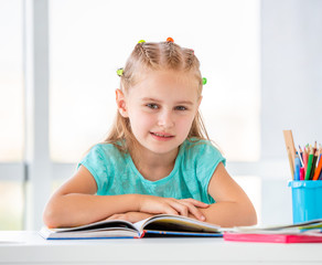 Cute schoolgirl sitting with open book