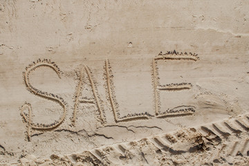 The word sale is painted on the sand. Beach background. View from above. The concept of summer, summer kanikkuly, vacation, holydays.