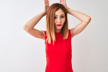 Fototapeta na wymiar Redhead businesswoman wearing elegant red dress standing over isolated white background Doing bunny ears gesture with hands palms looking cynical and skeptical. Easter rabbit concept.