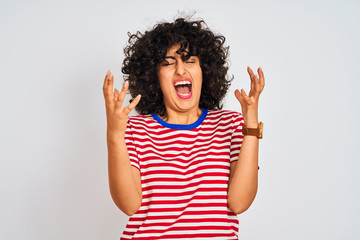 Young arab woman with curly hair wearing striped t-shirt over isolated white background celebrating mad and crazy for success with arms raised and closed eyes screaming excited. Winner concept