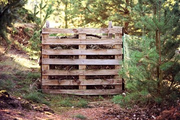 Home-made composter on a bright sunny day. the compost container is filled with branches and leaves.