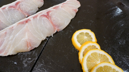 Pieces of snapper fillets with ice and lemon.
