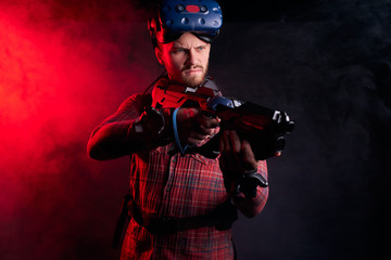 Young man holding virtual reality gun, ready to shoot. Studio shoot isolated over ultra violet background