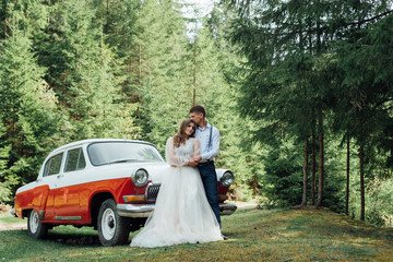 gentle stylish groom and bride on the background old fashioned car