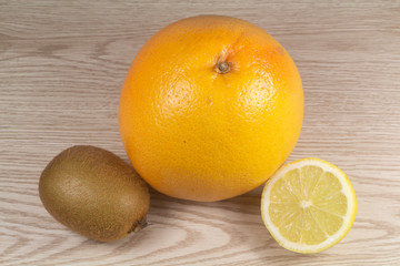 Grapefruit, kiwi and half lemon on wooden background