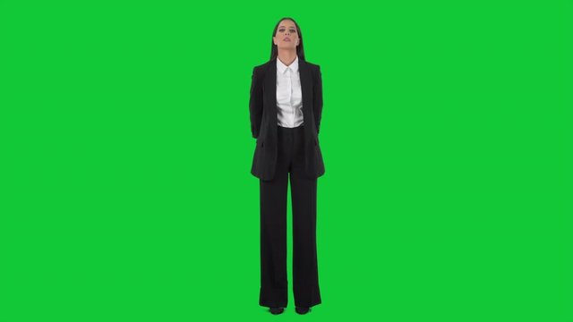 Young serious business woman at attention watching and listening with approval expression. Full length on green screen background. 