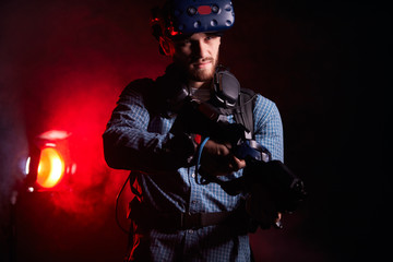 Portrait of young man holding VR weapon, wearing casual clothes playing virtual game. Isolated over smoky background