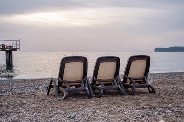 Three sun loungers stand on the beach by the sea