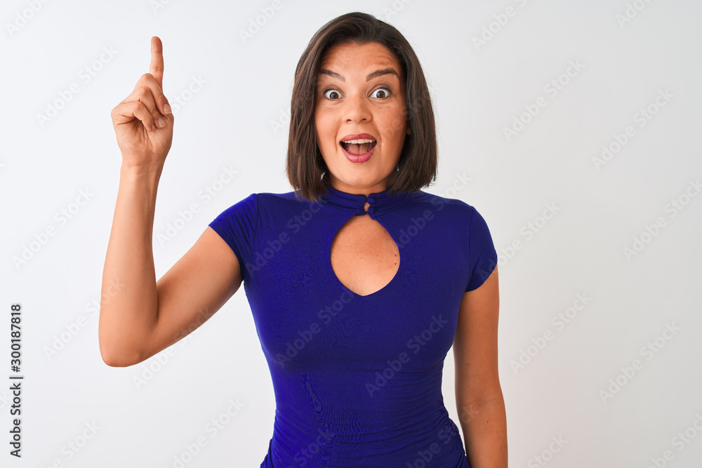 Wall mural young beautiful woman wearing blue elegant t-shirt standing over isolated white background pointing 