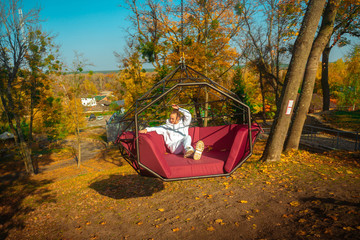 Girl rides on a swing over a cliff