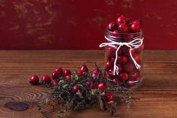 Immunity boosting treatments. Natural thyme, mint herbs and rosehip berries in a jar on a wooden background. Phyto therapy remedies, healthcare infusions.Cold and flu medicine,ethnoscience,homeopathy.