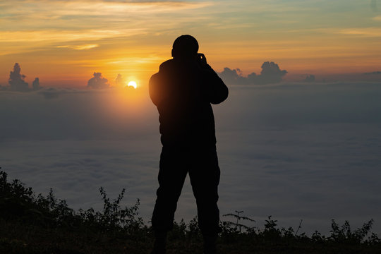 silhouette of a man photographing the landscape during sunset