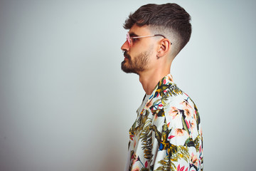Man with tattoo on vacation wearing summer shirt sunglasses over isolated white background looking...