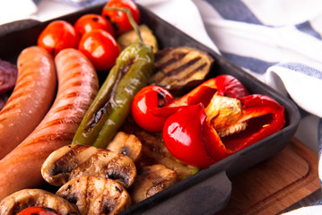 Grilled vegetables with sausages, tomatos, peppers and mushrooms on a barbecue 