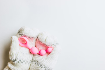 Christmas or New Year composition. Pink sex toy in female hands in knitted mittens on white background. Top view. Copy space. Flat lay. Christmas minimal concept.