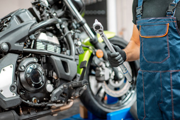 Obraz na płótnie Canvas Mechanic repairing motorcycle at the workshop