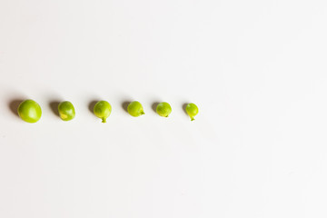 Fresh green peas scattered on a white background.