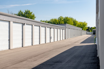 Row of storage units with garage doors with trees