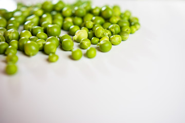 Fresh green peas scattered on a white background.