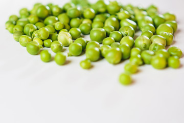 On a white background scattered with fresh green peas, there is a place for an inscription.