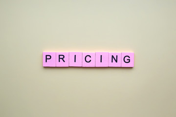 Pricing word wooden cubes on an yellow background.