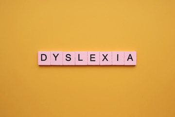 Dyslexia word wooden cubes on an yellow background. - obrazy, fototapety, plakaty