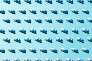 Trendy pattern made with Pharmaceutical medicine pills, tablets and capsules on bright light blue...