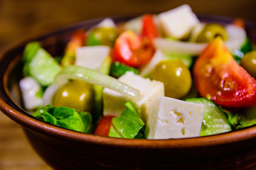 Ceramic plate with greek salad on wooden table
