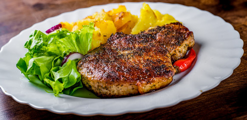 Pork Loin chops marinated meat Steak with vegetables slad and potato on wooden table background
