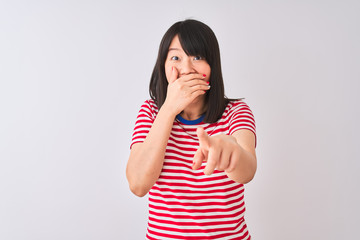 Young beautiful chinese woman wearing red striped t-shirt over isolated white background laughing at you, pointing finger to the camera with hand over mouth, shame expression