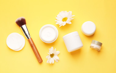 Different cosmetic creams with brush on color background