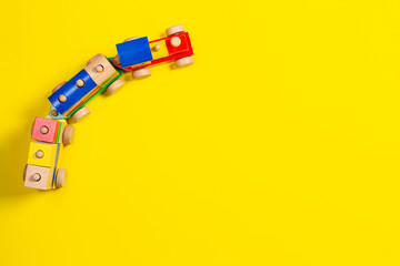 Wooden toy train with colorful blocks on yellow background