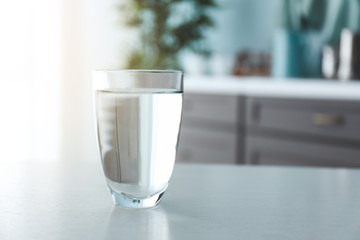 Glass of fresh water on table in kitchen