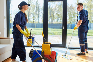 Man and woman co-workers of cleaning company enjoy working in cleaning service, process of cleaning...
