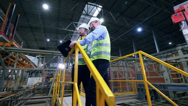 Engineers work with a laptop at a modern industrial factory. Professional factory workers at factory facility.