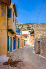 Narrow street with colorful stone houses in the old village of Pano Elounda, Crete, Greece. 
