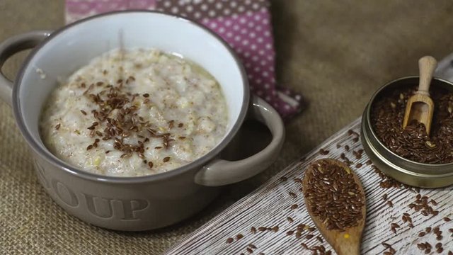 Linen seeds fallen onto bowl oatmeal. Slow motion