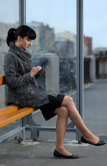Girl with phone at bus stop