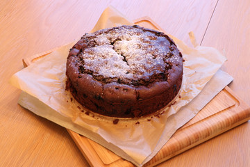 Christmas cake on a festively decorated table on baking paper and a wooden stand.