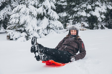 Fototapeta na wymiar Woman having fun in heavy snow with a sleigh.