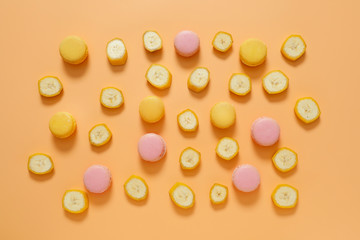 Tasty macarons with banana slices on color background