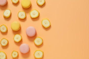 Tasty macarons with banana slices on color background
